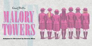 A group of girls in school uniforms smiling and standing together in a sunny outdoor setting.