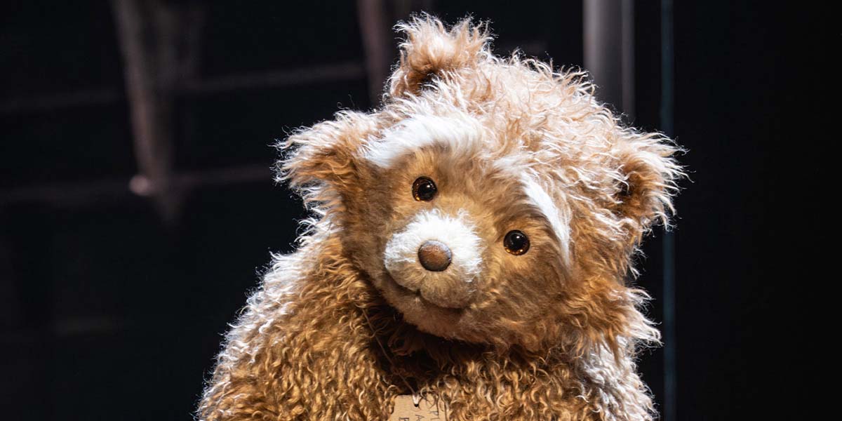 A vibrant stage scene from Paddington The Musical, featuring colourful costumes and dynamic poses of performers.