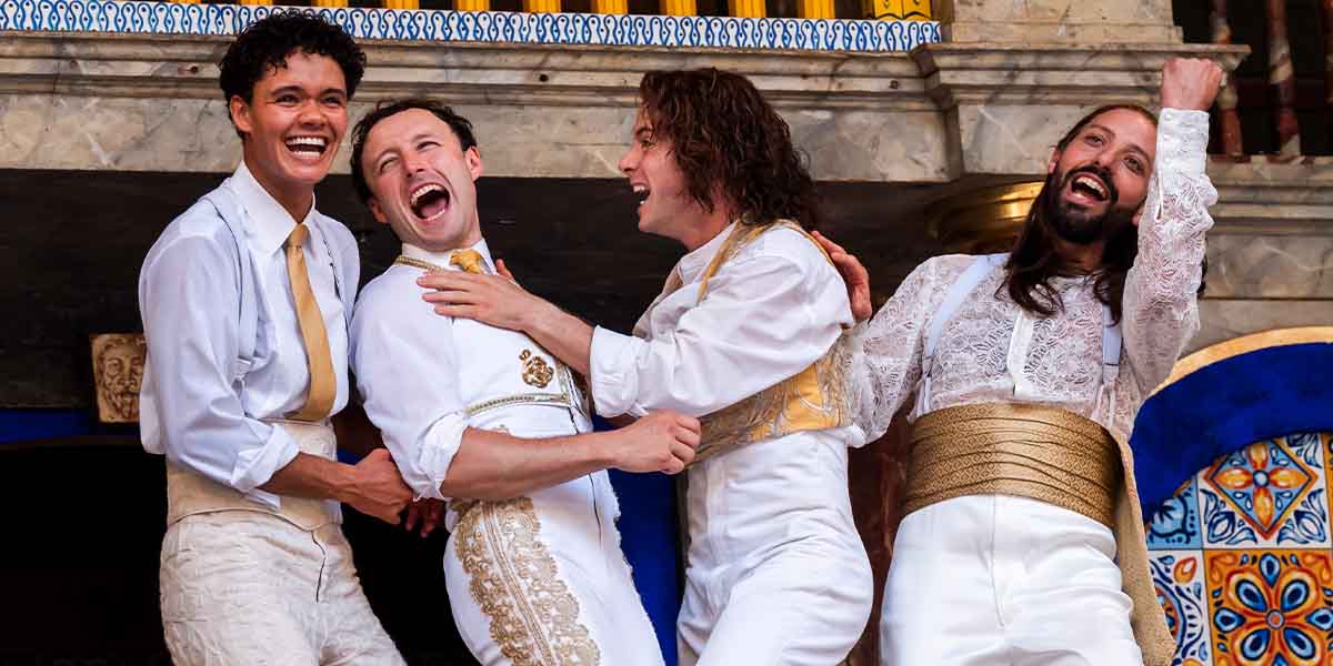 Jax Guerrero as Dumaine, Ned Costello as King of Navarre, Philip Labey as Longaville, and Philip Arditti as Berowne on stage.