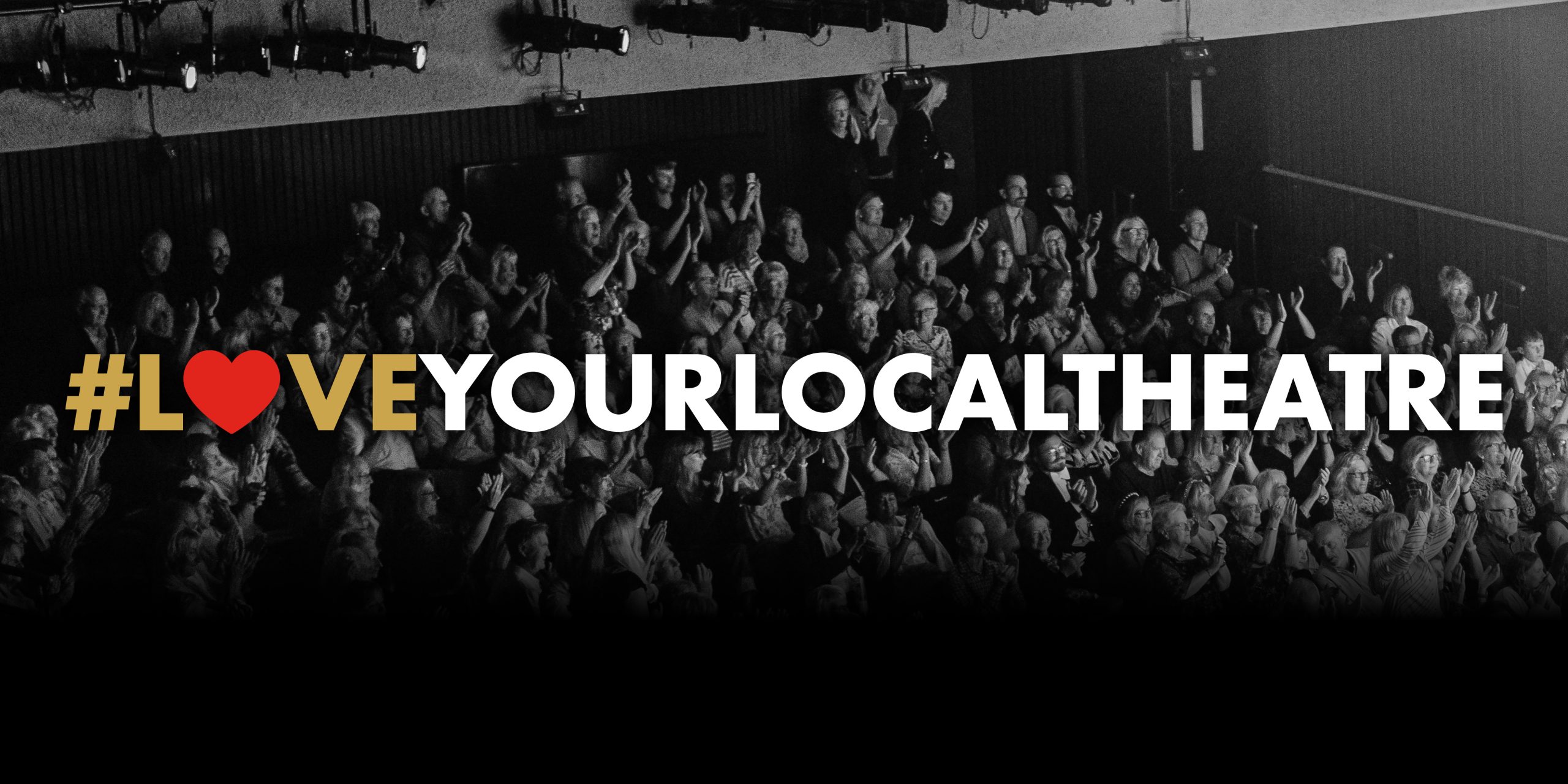 A black and white image of an audience with text in front that reads #LOVE YOUR LOCAL THEATRE