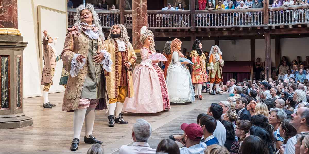 The cast of As You Like It performs on stage at Shakespeare's Globe, dressed in period costumes.