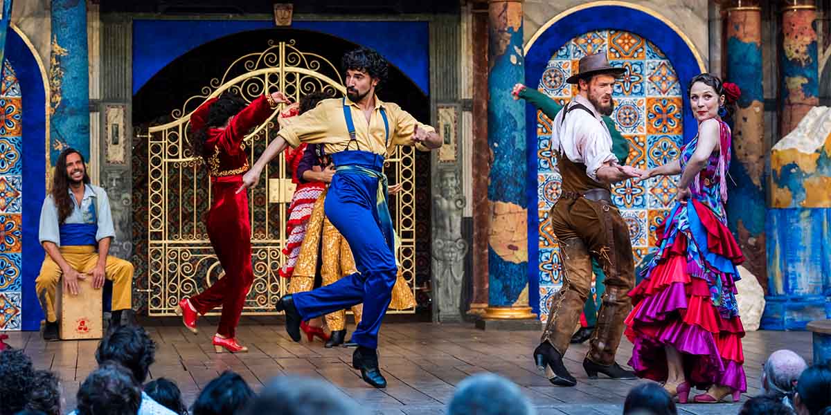 The cast of Love's Labour's Lost poses together on stage at Shakespeare's Globe, dressed in period costumes.