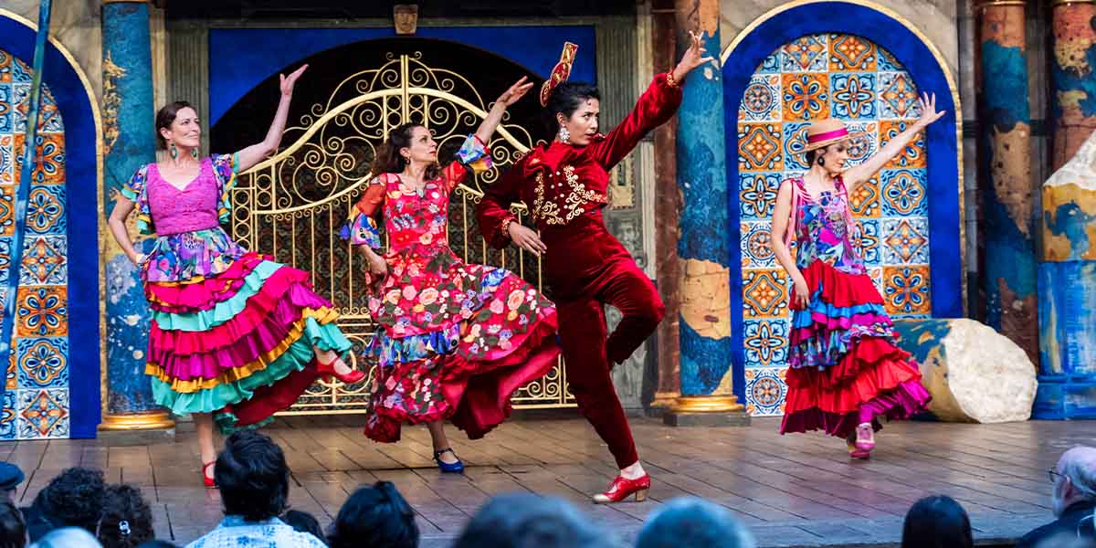 The cast of Love's Labour's Lost poses together on stage at Shakespeare's Globe, dressed in period costumes.