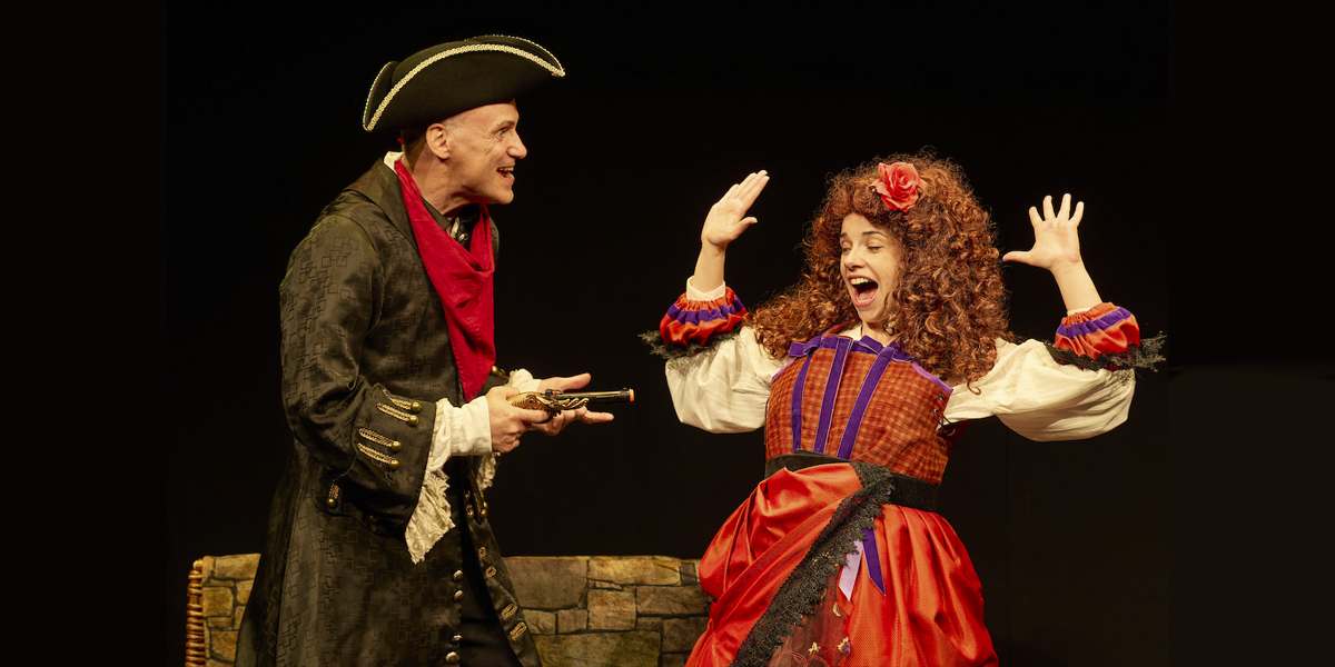 Dick T. in a vibrant costume, performing energetically on stage with a historical backdrop and audience visible.