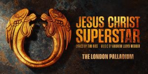 A dramatic scene from Jesus Christ Superstar featuring performers in vibrant costumes on a dimly lit stage.
