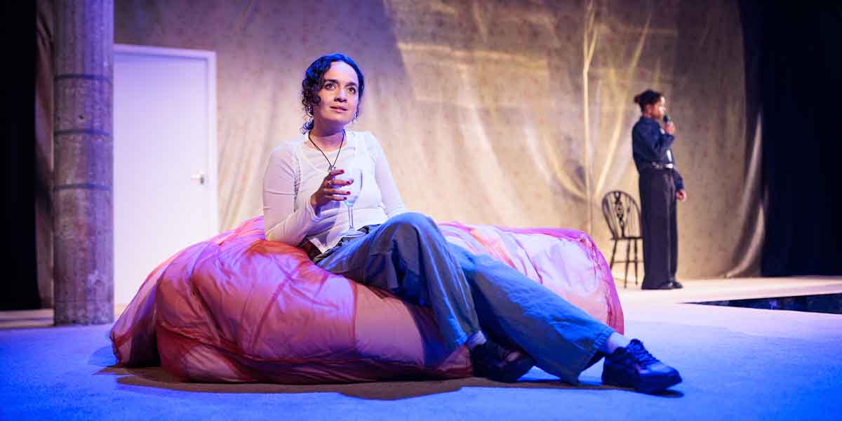 Nadi Kemp-Sayfi as Ivy sits on a pink beanbag, while Francesca Amewudah-Rivers as Ash stands behind her.