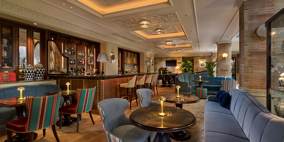 A stylish cocktail bar featuring elegant seating, dim lighting, and a variety of colourful cocktails on display.