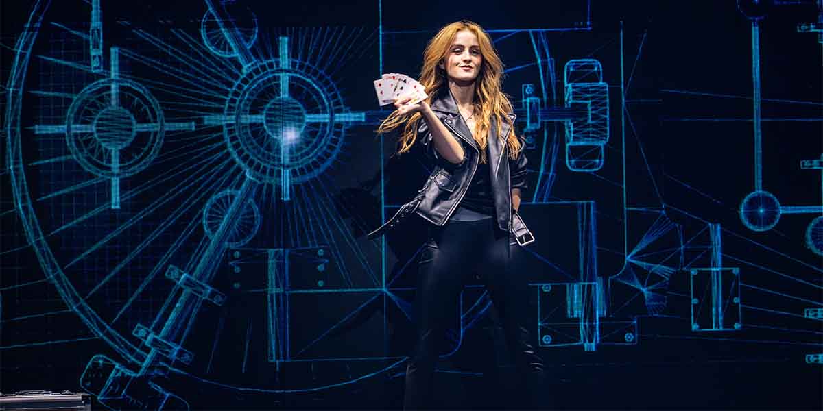 Gabriella Lester holds playing cards, wearing a black leather jacket, against a blue graphic backdrop.