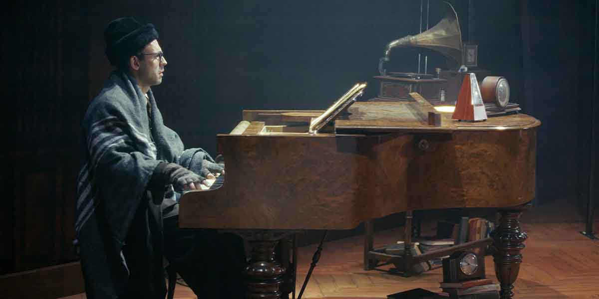 A man in a dark coat plays a grand piano, surrounded by vintage decor and soft lighting.
