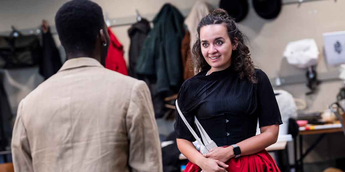 Jyuddah Jaymes and Nadi Kemp-Sayfi rehearsing for Sherlock Holmes, with costumes and props in the background.