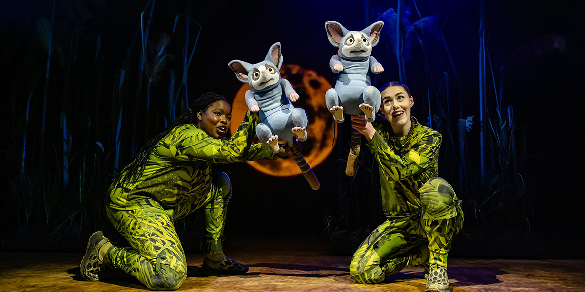 A scene from "The Enormous Crocodile The Musical" featuring vibrant costumes and a jungle backdrop.