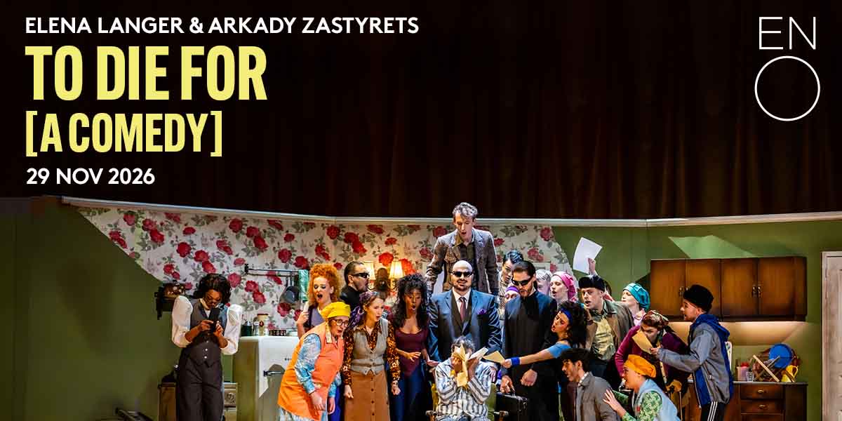 A diverse cast performs energetically on stage, surrounded by a floral backdrop and kitchen set.