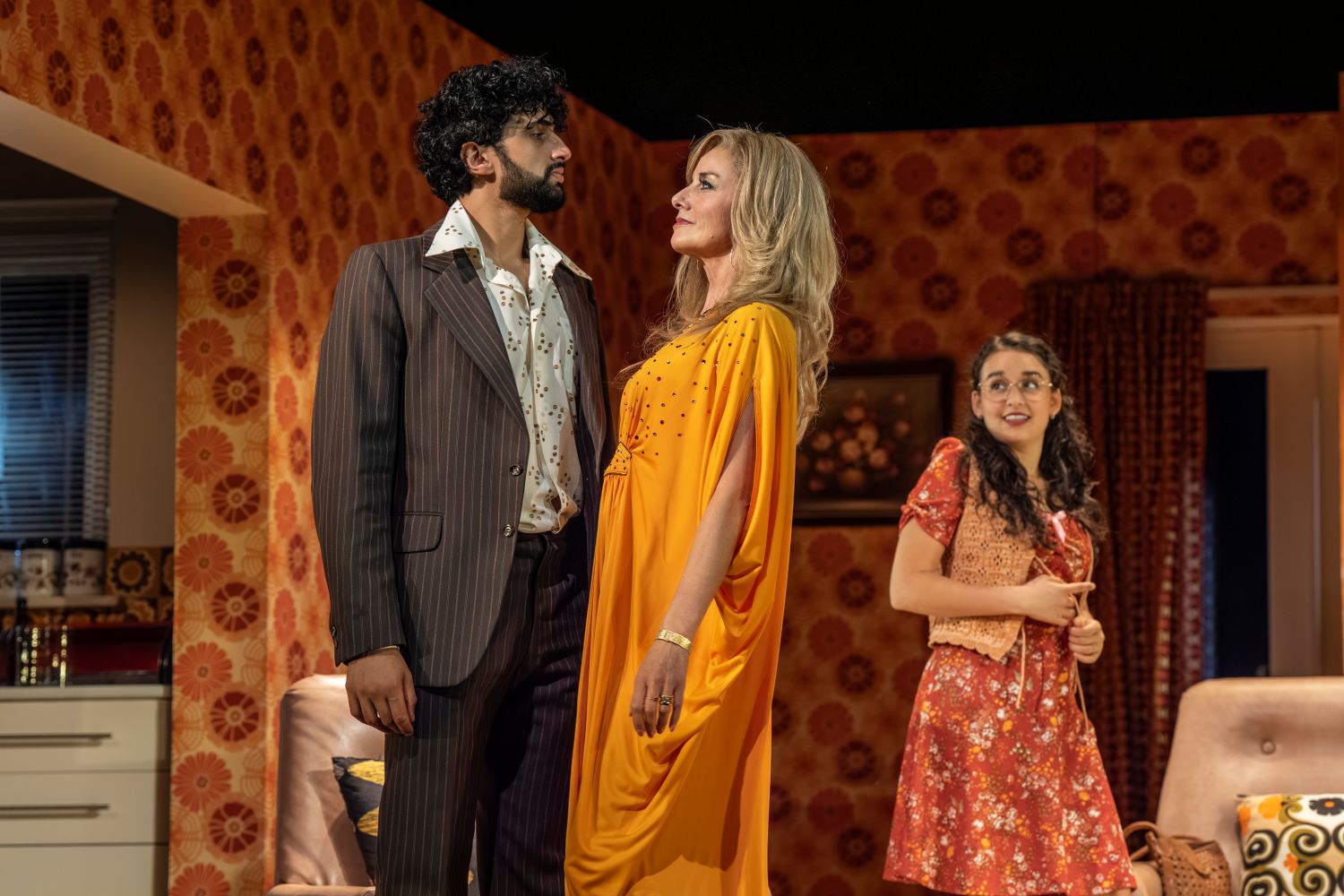 Omar Malik, Tamzin Outhwaite, and Lauren Patel pose together, smiling, in a vibrant party setting.