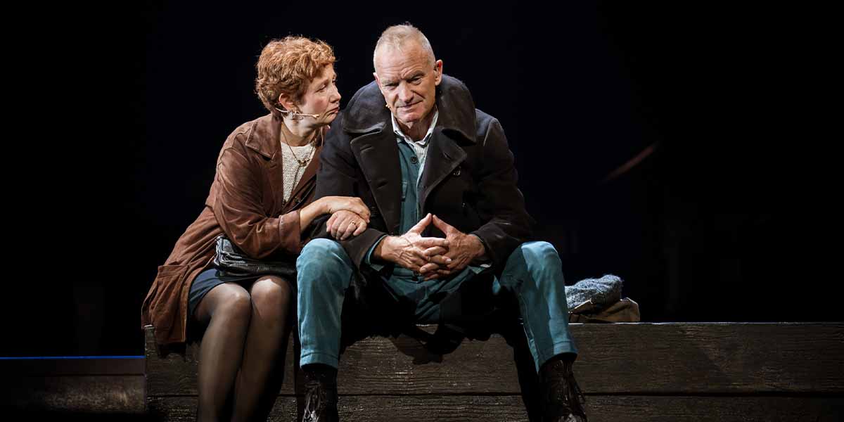 Jackie Morrison and Sting sit closely on a wooden platform, sharing an intimate moment in The Last Ship.