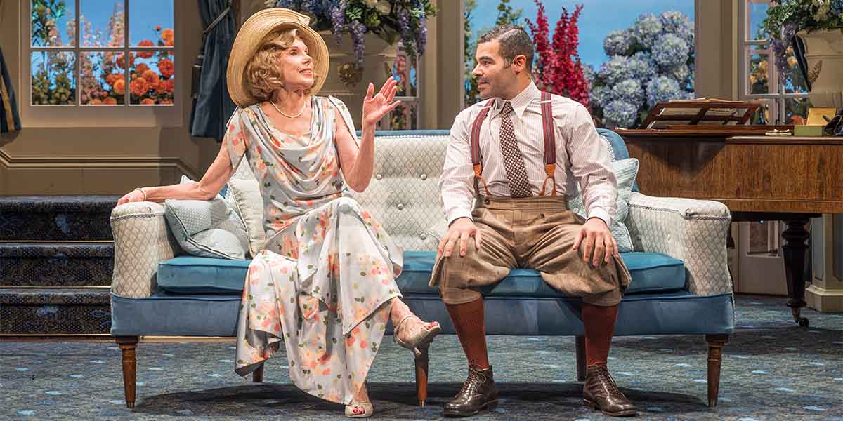 Christine Baranski as Judith Bliss and Ash Hunter as Sandy Tyrell, both in a stylish living room setting.