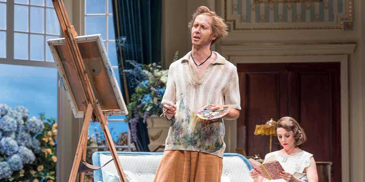 Will Close, in a knitted top, holds a paint palette while Ophelia Lovibond reads nearby.