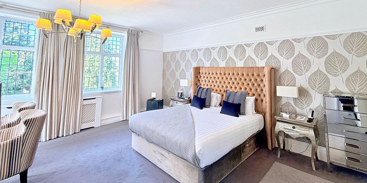 A luxurious hotel room featuring a king-sized bed, elegant decor, and large windows with city views.