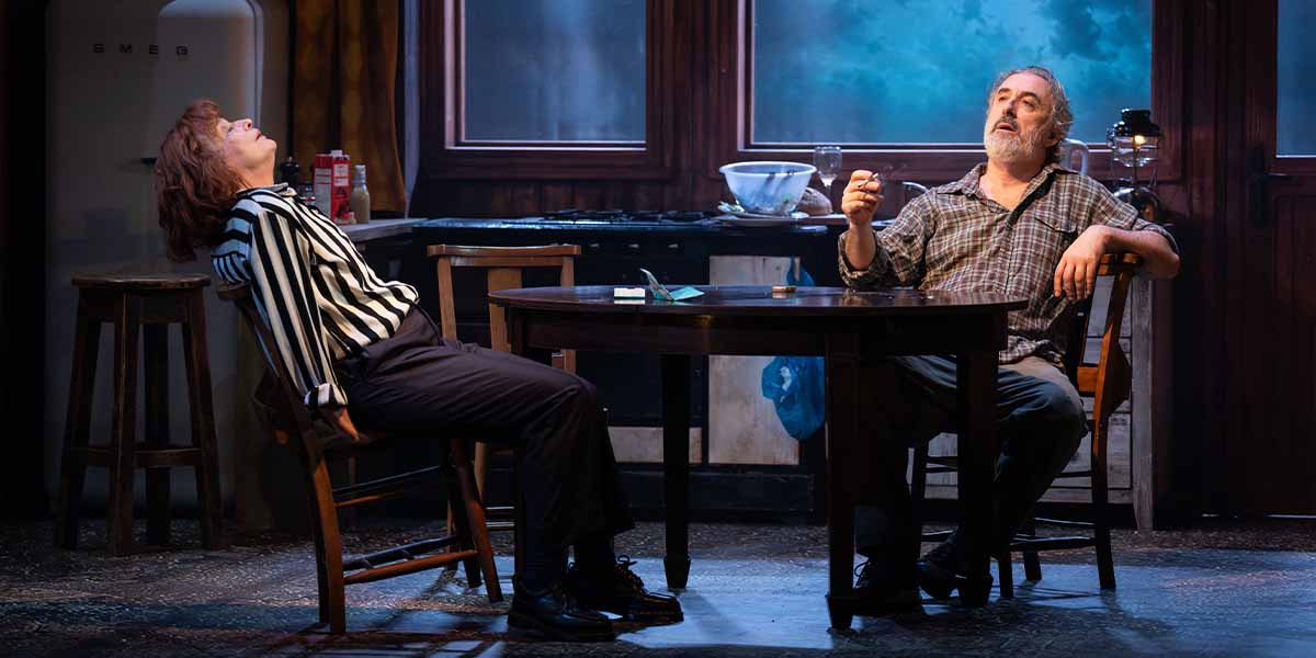 Kerry Fox leans back in a chair, while Declan Conlon gestures thoughtfully at a table.