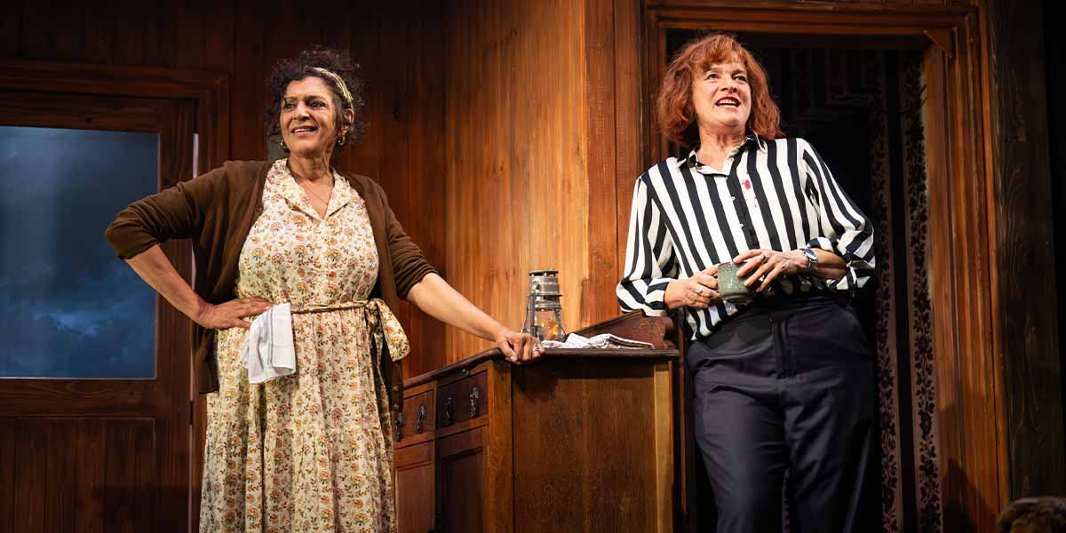 Meera Syal and Kerry Fox stand in a wooden room, smiling and engaging with each other.