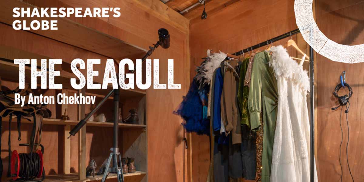 Costumes for "The Seagull" hang on a rack in a wooden room, with a spotlight and headphones visible.