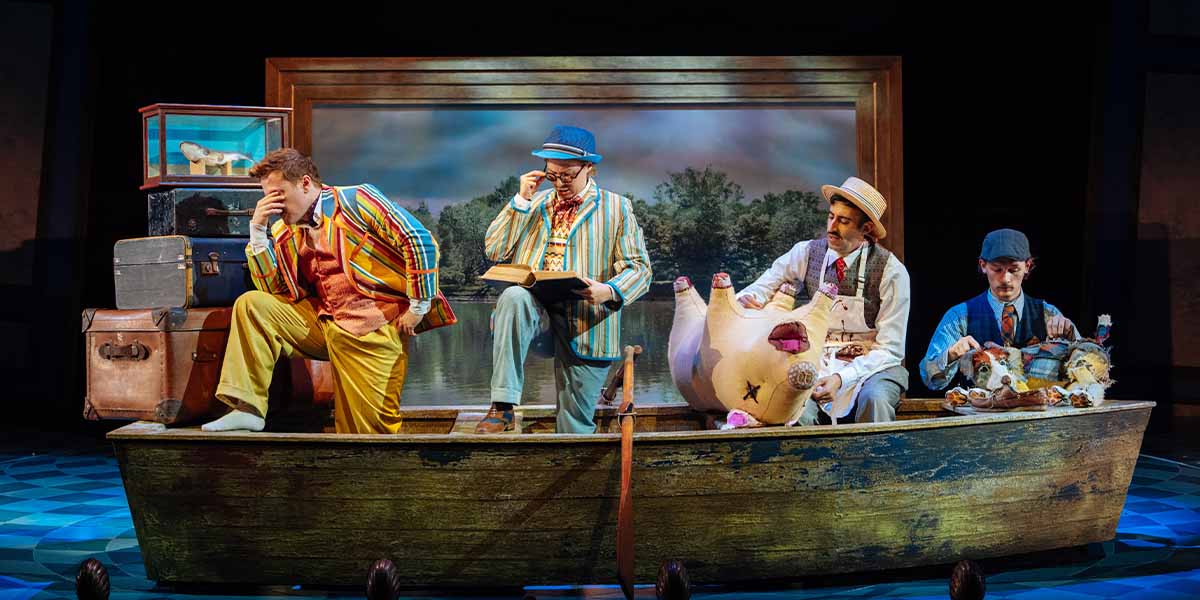 Three actors in period costumes pose together, smiling, with a theatre backdrop and soft lighting.