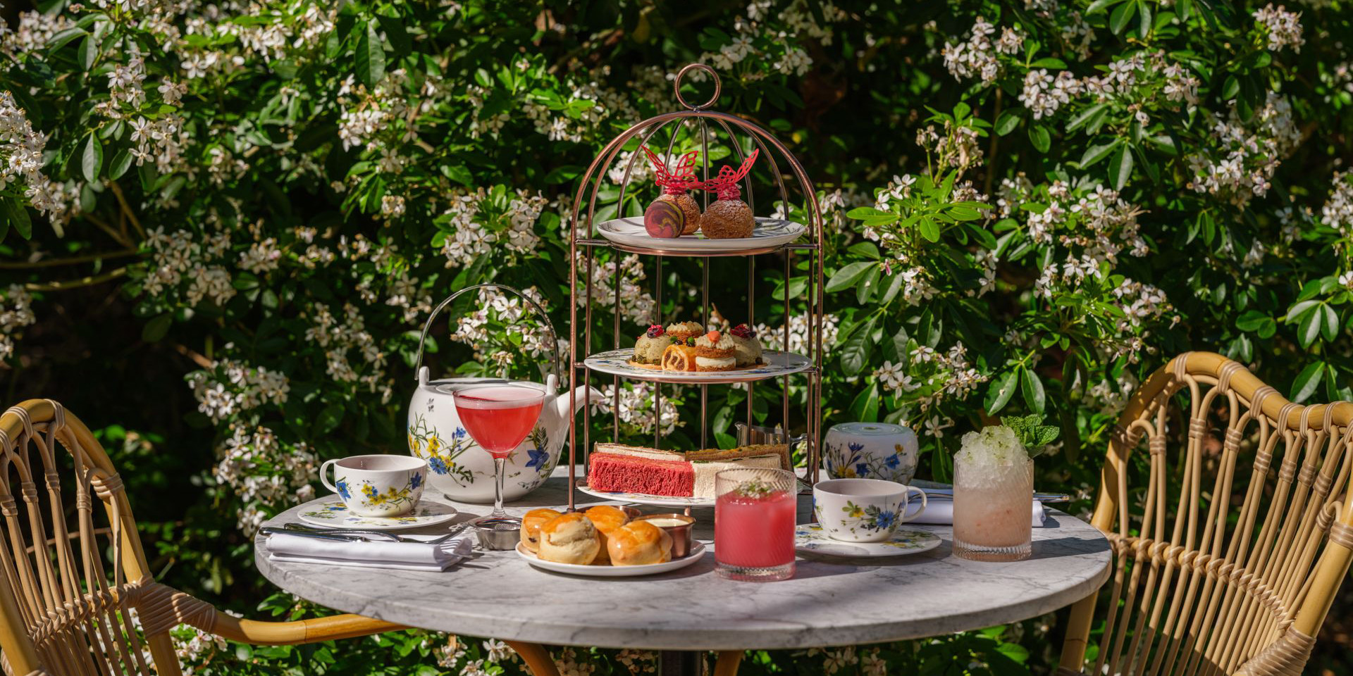 A beautifully arranged afternoon tea set with delicate pastries and tea cups in a garden setting.