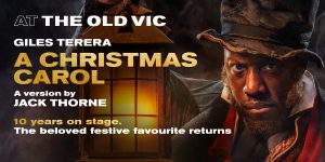 A scene from "A Christmas Carol" featuring characters in Victorian costumes, with festive decorations in the background.